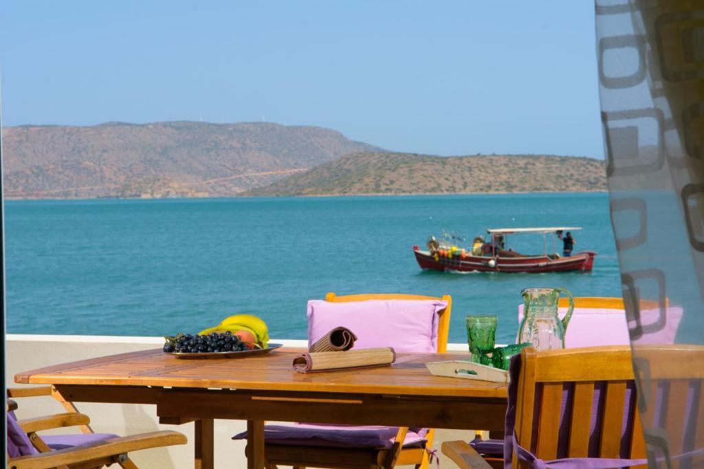 a table with a book and a boat in the water at Kristallia in Elounda