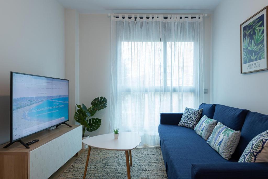 un salon avec un canapé bleu et une télévision dans l'établissement Eli Canteras-Parking-Airco by CanariasGetaway, à Las Palmas de Gran Canaria