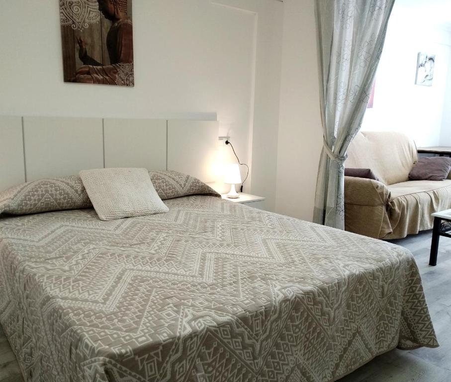 a bedroom with a bed and a couch and a window at Apartaloft LA CELESTINA in Almagro