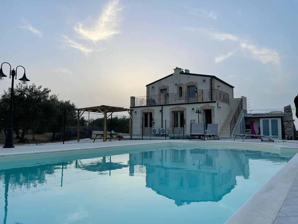 a villa with a swimming pool in front of a house at Bàcula Nzícula Marzamemi in Marzamemi
