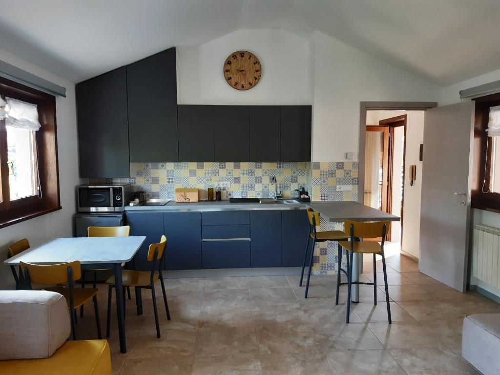 a kitchen with blue cabinets and tables and a clock on the wall at Appartamento SG in Sistiana