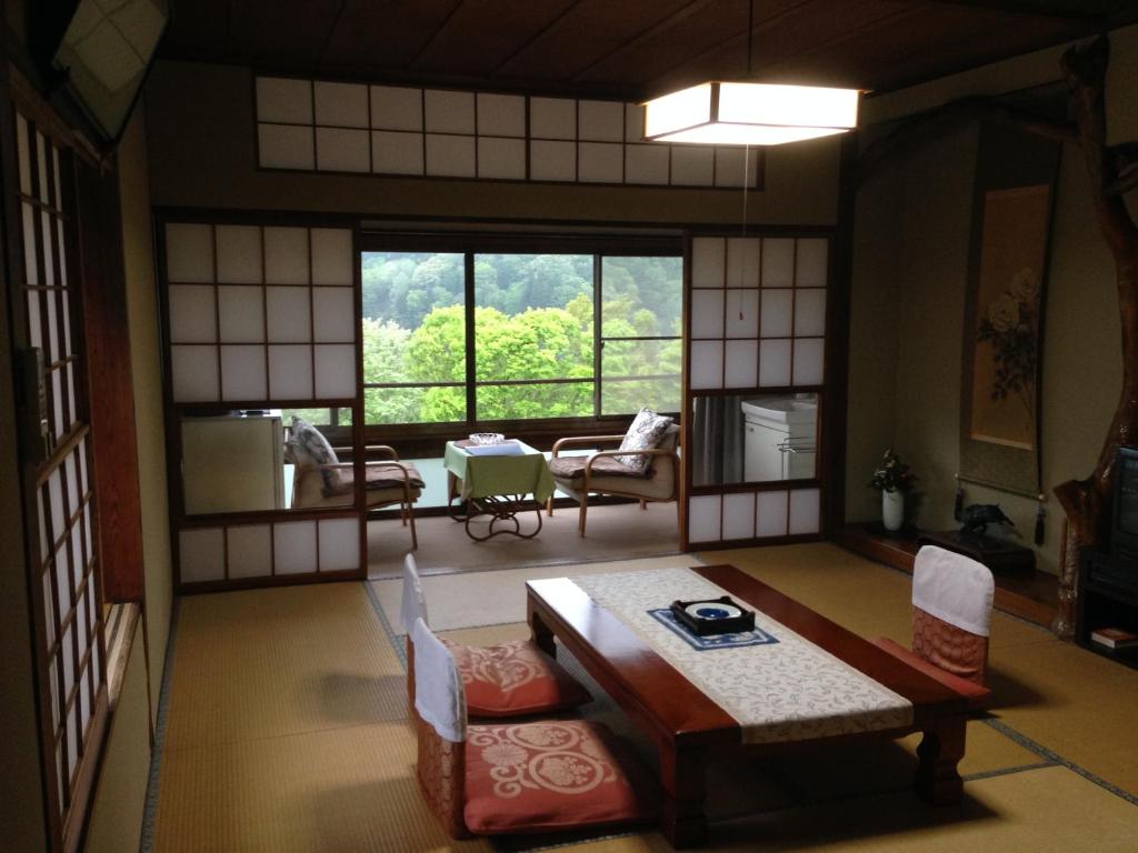 a room with a table and chairs and a large window at Kofukan in Myoko