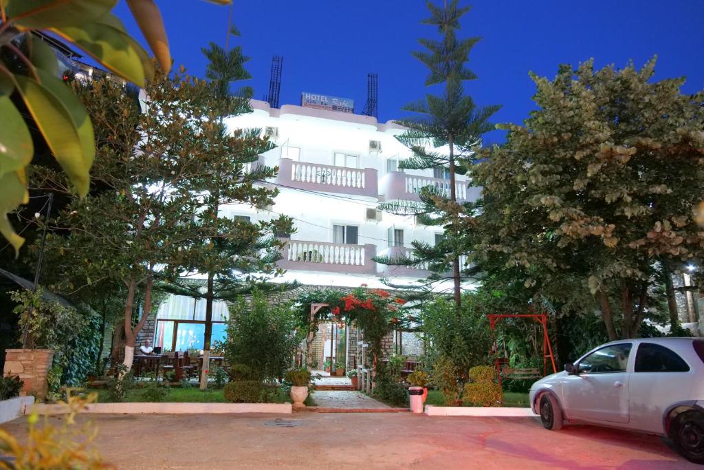 un edificio blanco con un coche aparcado delante de él en Hotel Rixhi, en Sarandë