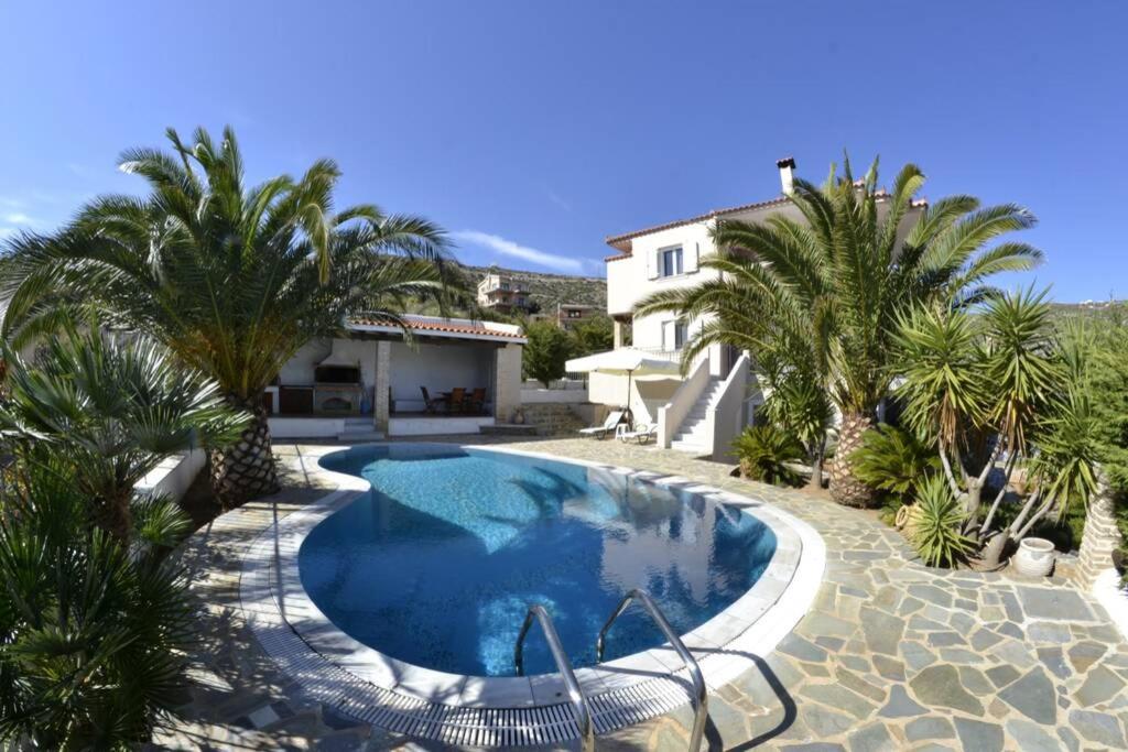 a swimming pool with palm trees and a house at Luxury Villa with swimming pool in Aliveri