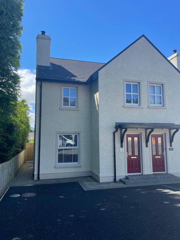 a house with a red door on a street at The Clara, Ballycastle in Ballycastle