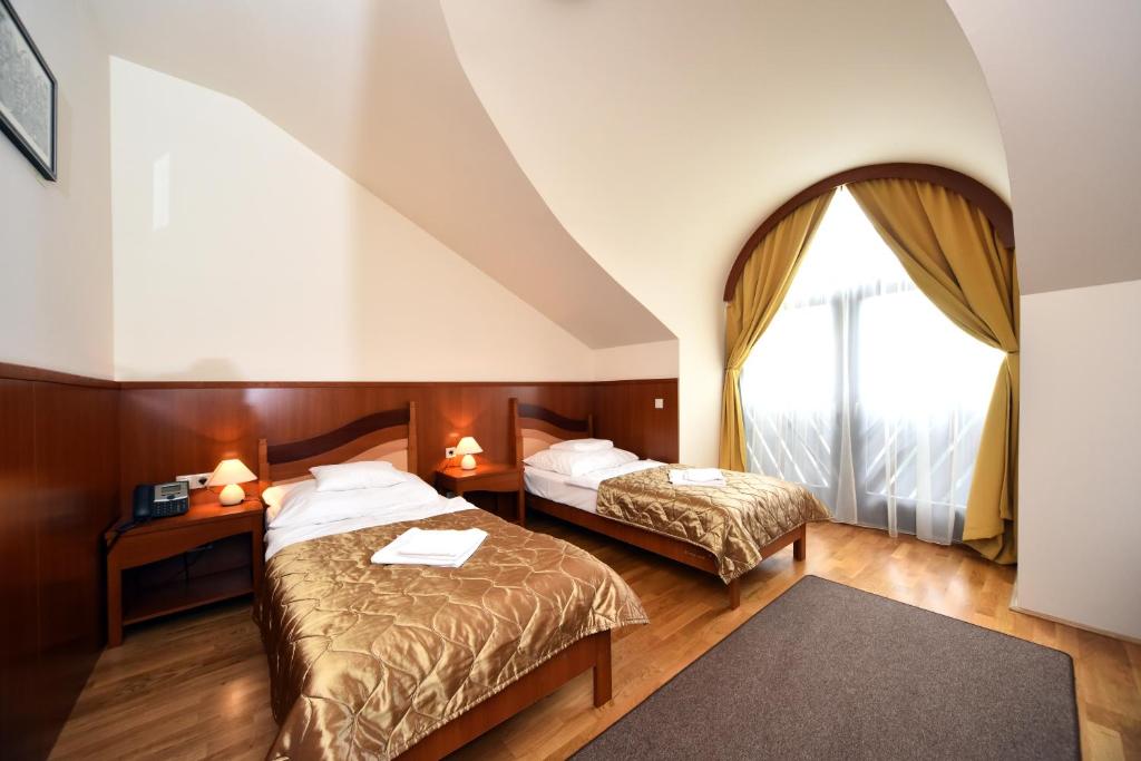 a hotel room with two beds and a window at Hotel Kumánia in Kisújszállás