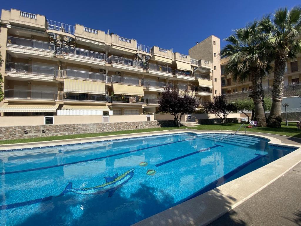una gran piscina frente a un edificio en R123 Apartamento en la planta baja con piscina cerca de la playa en Calafell