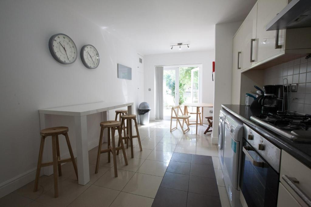 a kitchen with a counter and some stools in it at Tooting Rooms by DC London Rooms in London