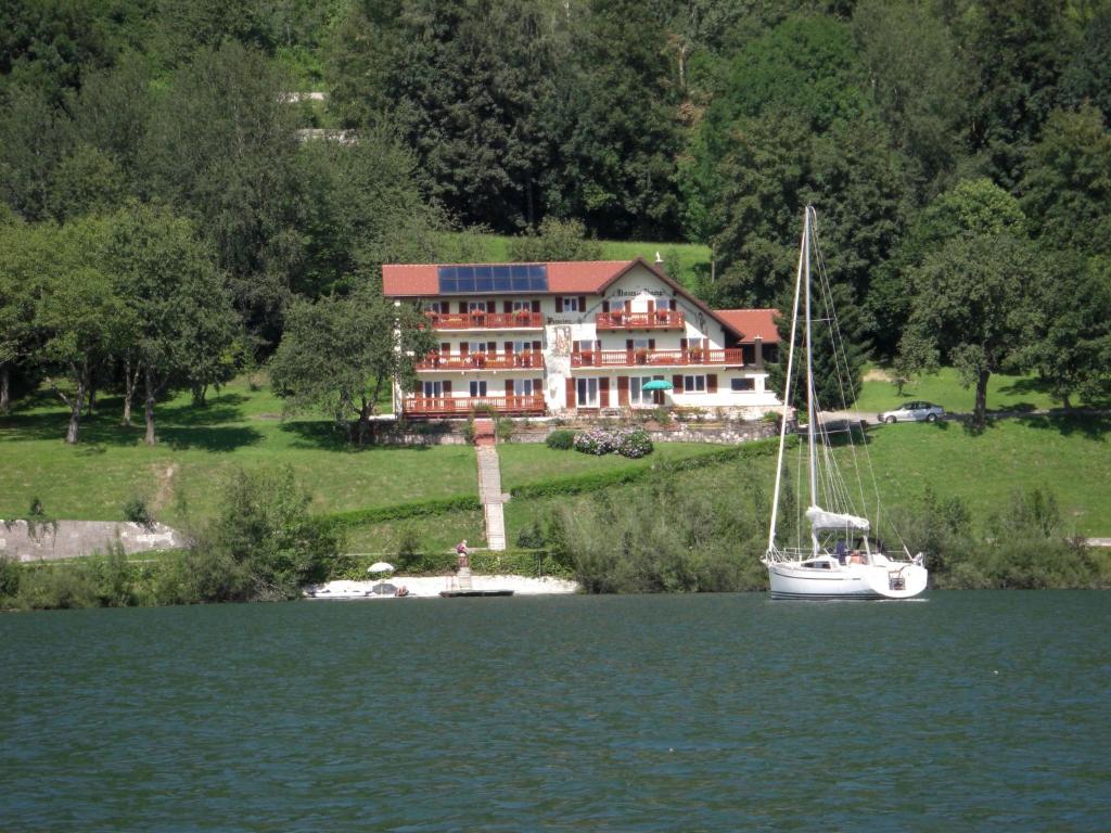 a boat in the water in front of a large house at Haus am Hang in Innerschwand am Mondsee