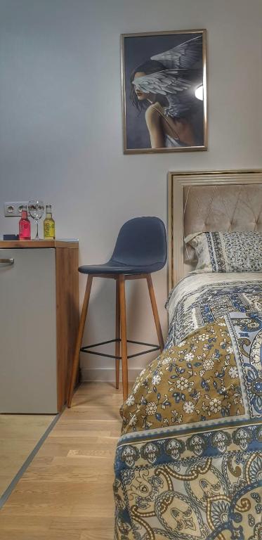 a bedroom with a blue chair next to a bed at Skyline by Nights & Smiles in Tuzla