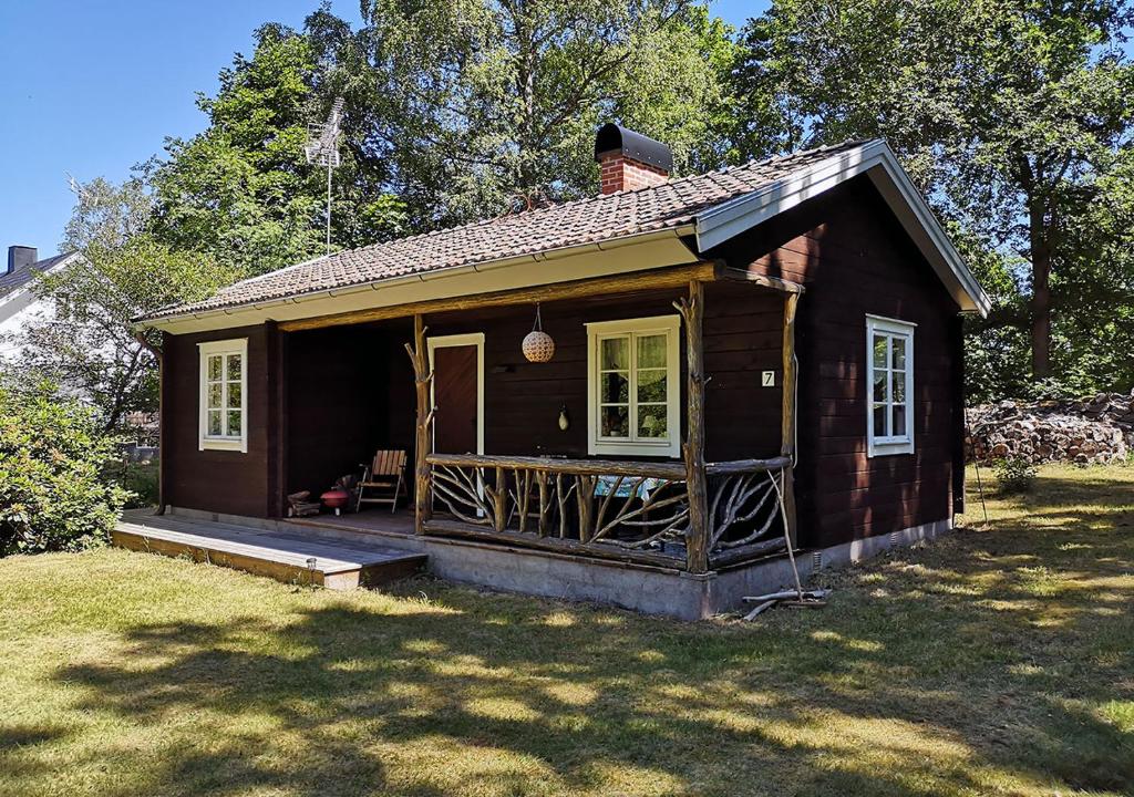 une petite maison avec une terrasse couverte sur un champ dans l'établissement Mysig stuga med öppen spis och uteplats, à Fröseke