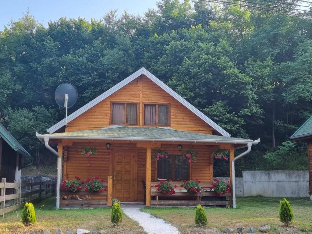 uma casa de madeira com flores em frente em Brvnara Sljivic em Kraljevo