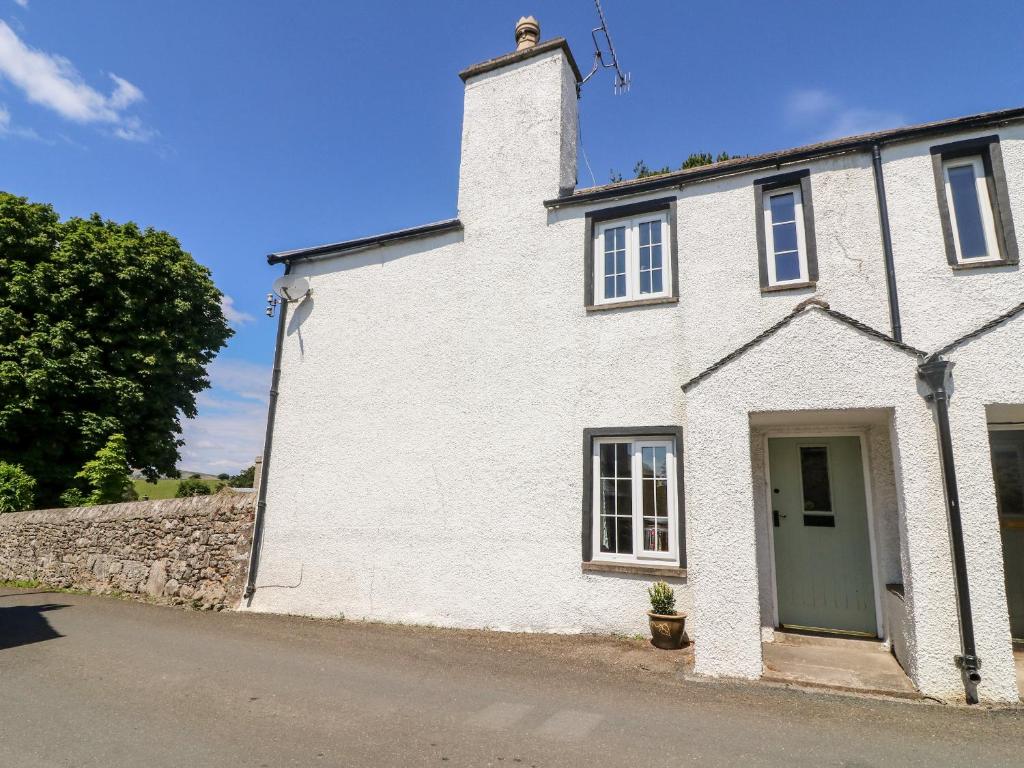 a white house with a green door on a street at St Peters Cottage in Milnthorpe