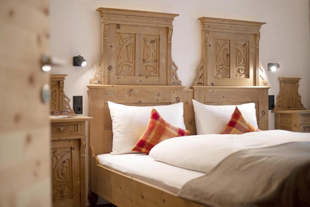 a bedroom with a bed with a wooden headboard and pillows at Archehof Hochzirm Lodge Anton in Campo Tures