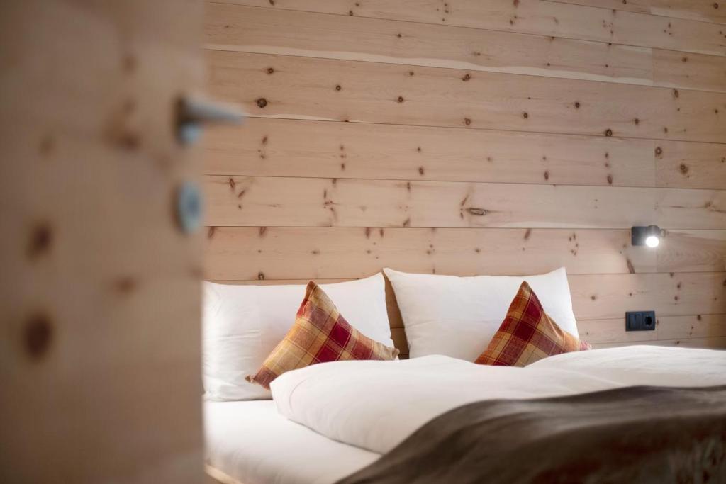 um quarto com uma cama com lençóis brancos e almofadas em Archehof Hochzirm Lodge Greti em Campo Tures