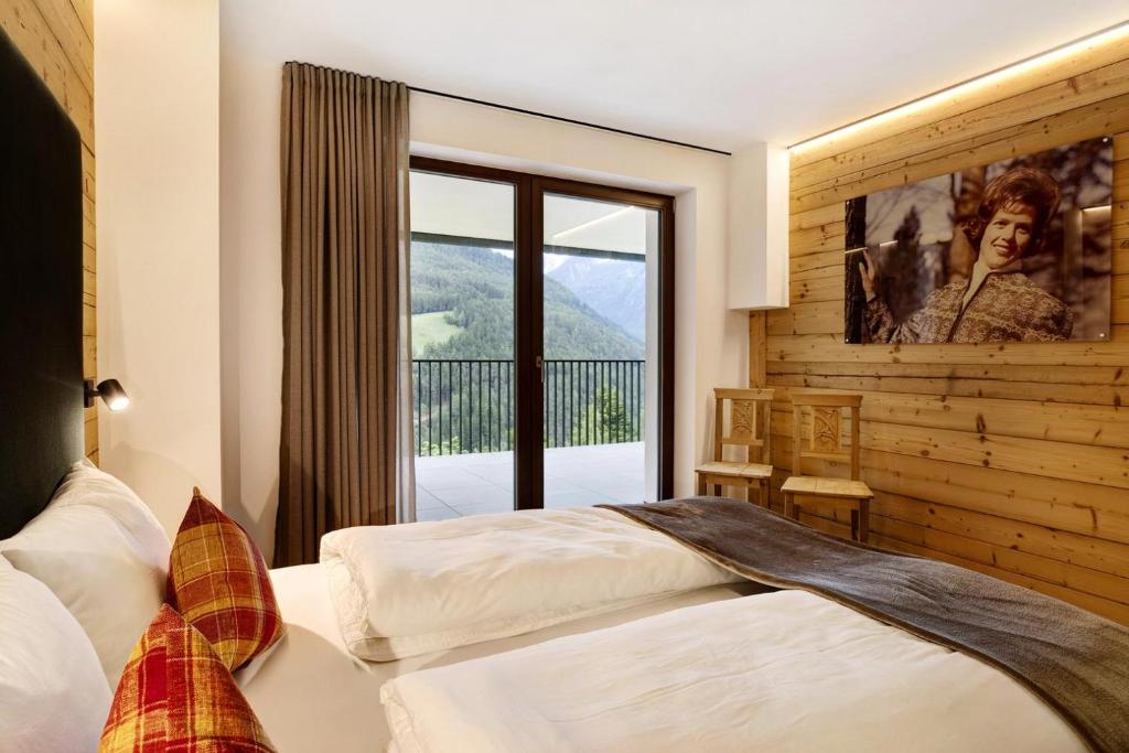 a bedroom with a bed and a large window at Archehof Hochzirm Lodge Anna in Campo Tures