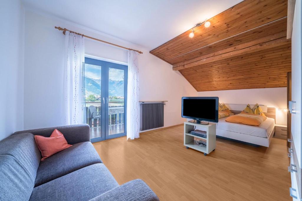 een woonkamer met een bank en een televisie bij Apartment Tschigat Leilichhof in Lana di Sotto