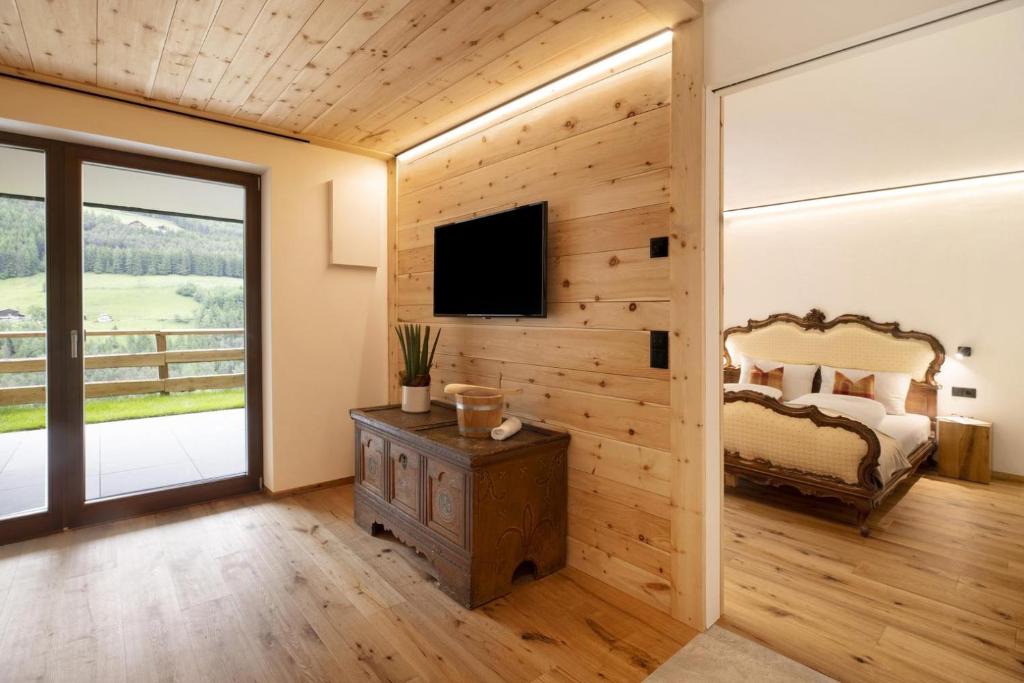 a bedroom with a wooden wall with a tv in it at Archehof Hochzirm Lodge Franz in Campo Tures