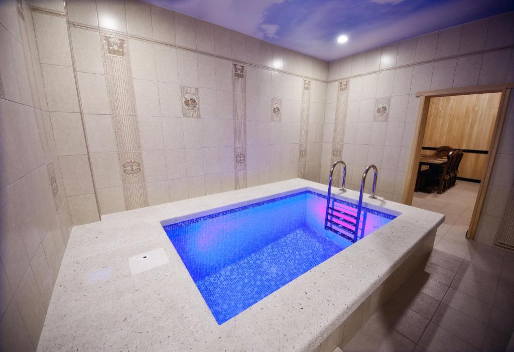 a bathroom with a large tub with blue water at Favorit Hotel in Gelendzhik