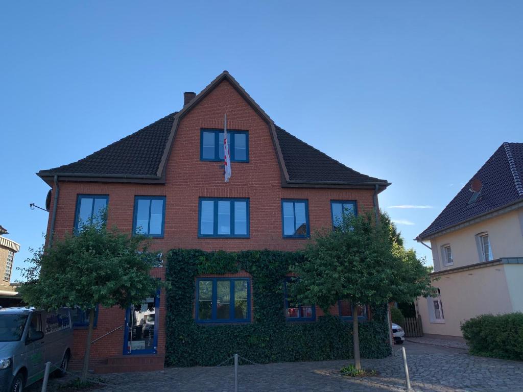 una casa de ladrillo rojo con árboles delante de ella en De Isenboner Wankendorf, en Wankendorf