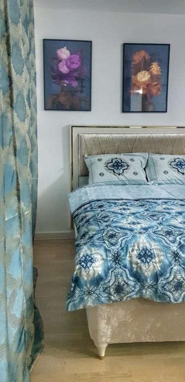 a bedroom with a bed with a blue and white comforter at Passion by Nights & Smiles in Tuzla