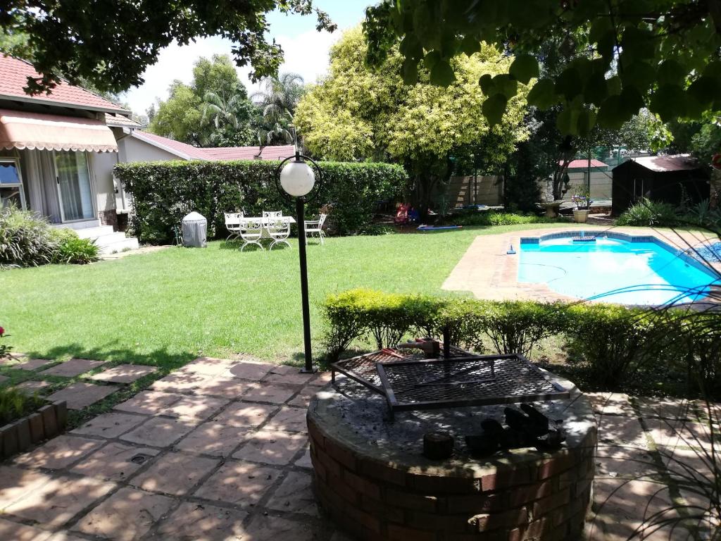een tuin met een zwembad en een huis bij Roosboompies Guest Suite in Centurion