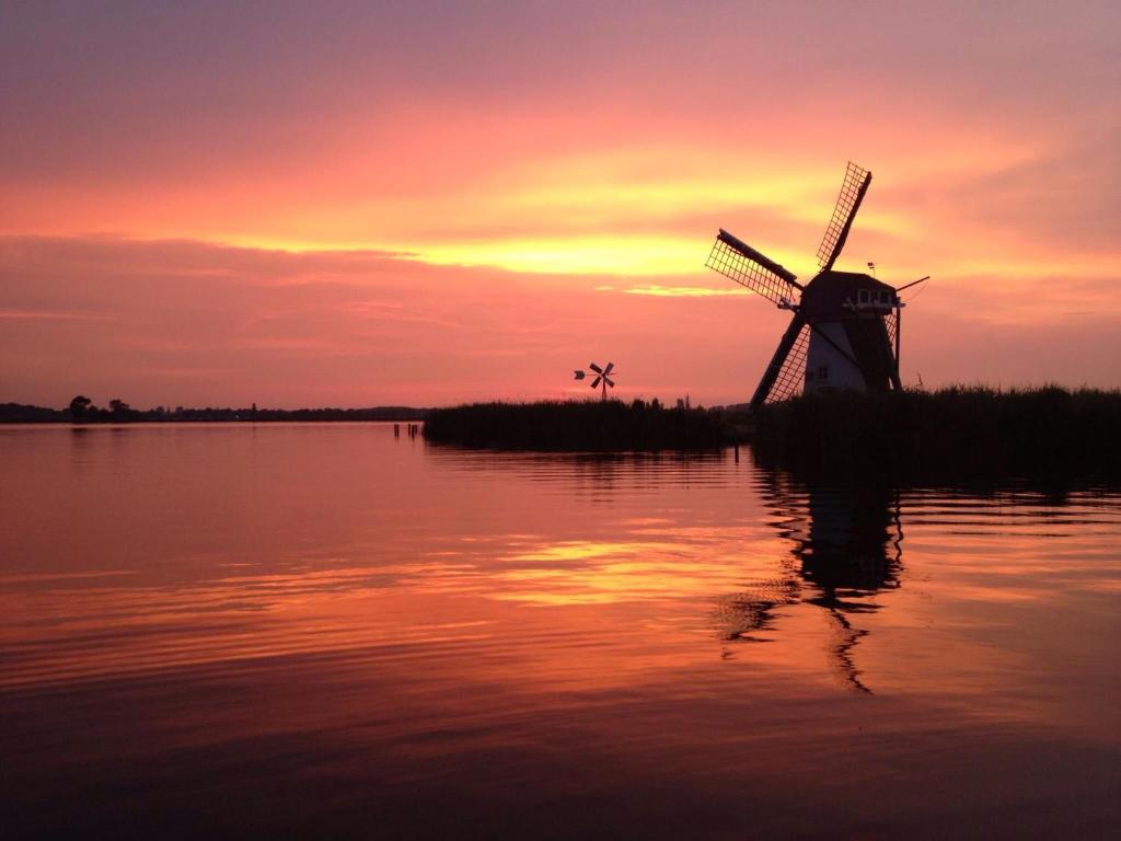 a windmill on an island in the water at sunset at Pura Vida Panorama in Oud-Ade
