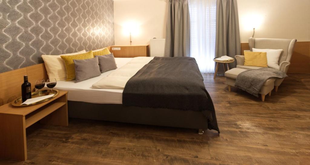 ein Schlafzimmer mit einem großen Bett und einem Stuhl in der Unterkunft Gästehaus Zehmerhof bei Erding in Walpertskirchen