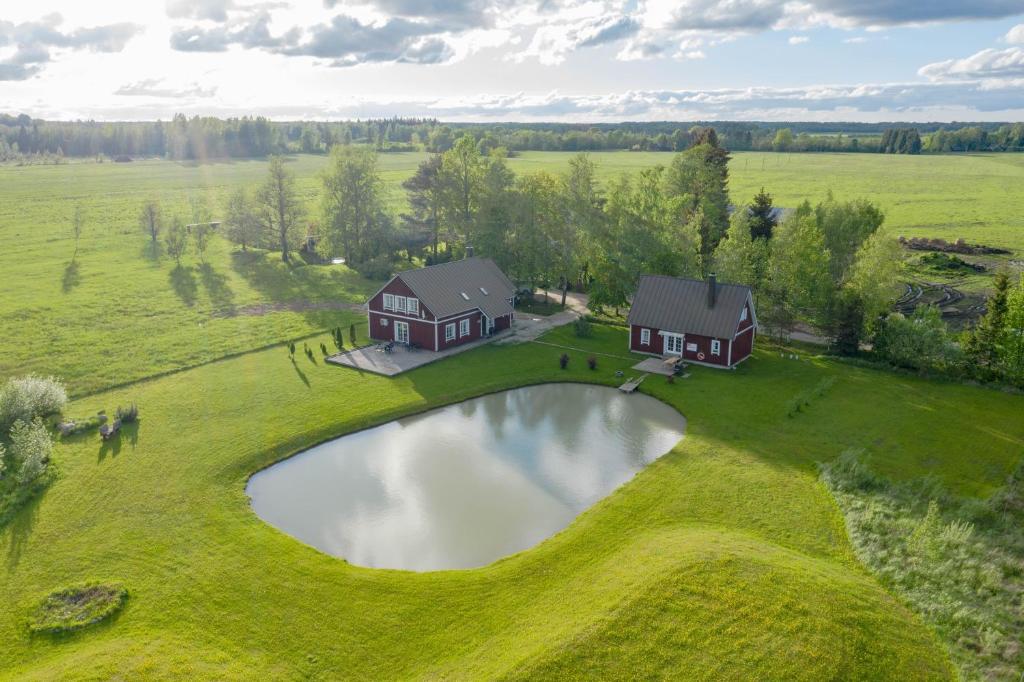 eine Luftansicht eines Hauses auf einem Feld mit einem Teich in der Unterkunft Põnka Guesthouse in Jõesuu