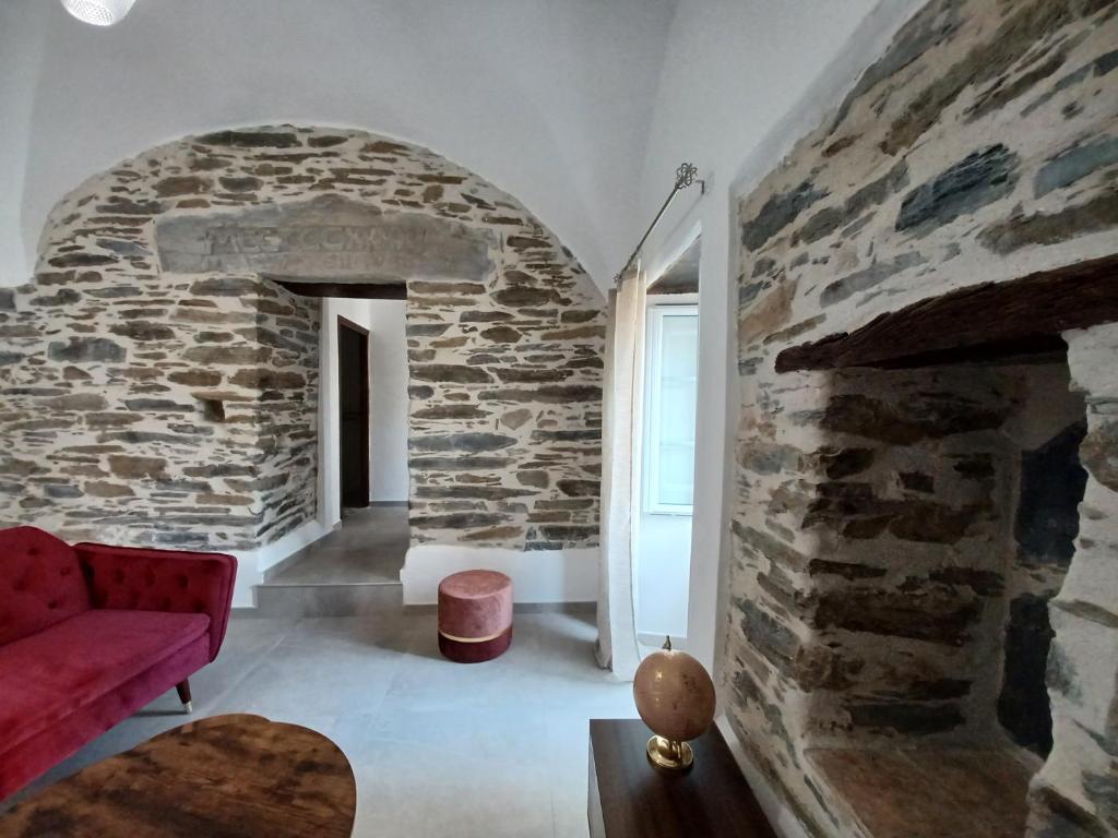 a living room with a stone wall and a red couch at Casa Pernice in Penta-di-Casinca