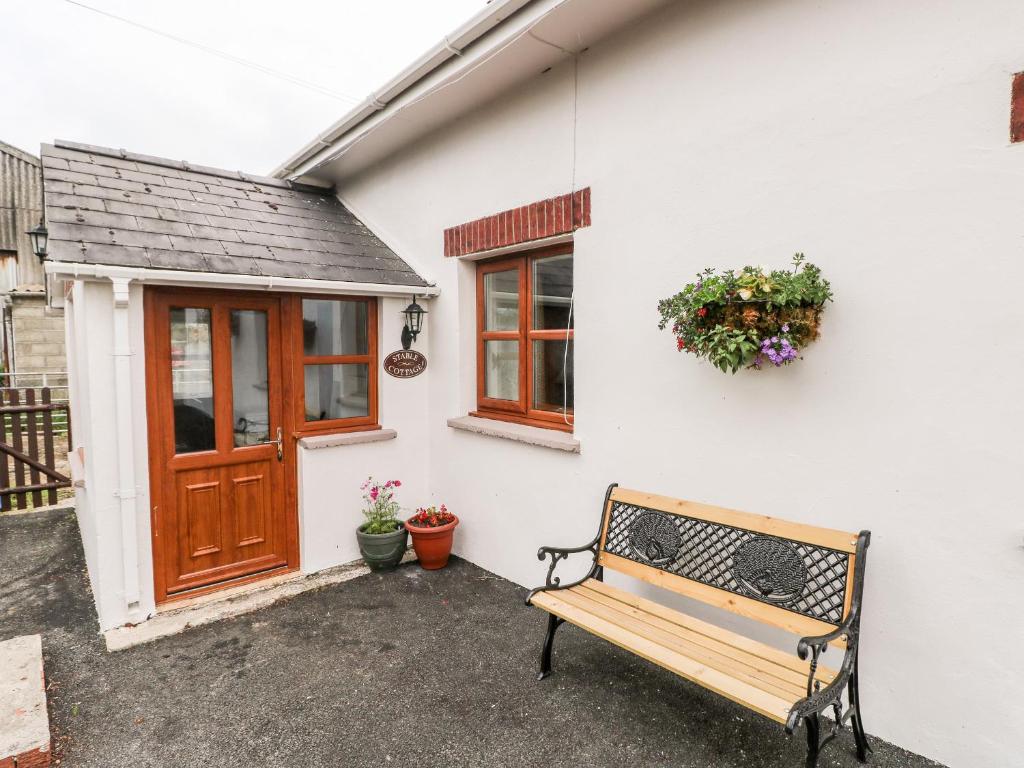 a bench in front of a white building with a door at Stable Cottage in Haverfordwest