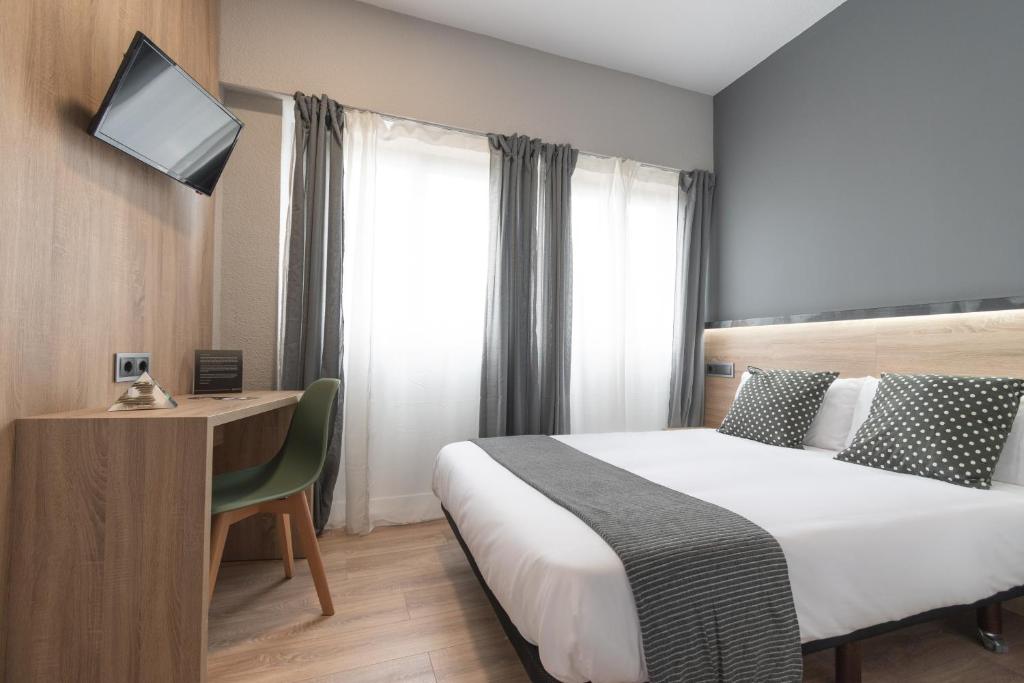 um quarto de hotel com uma cama e uma secretária com um computador em Alda Centro Pamplona em Pamplona