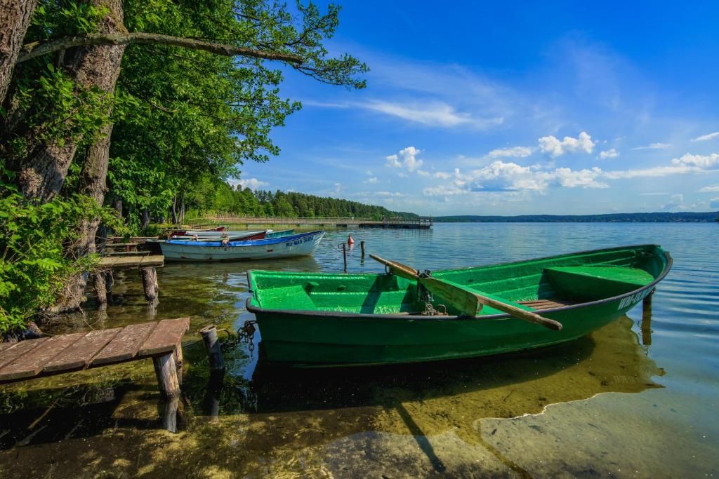 a green boat on the water next to a dock at Chata z Bala Mierki in Mörken