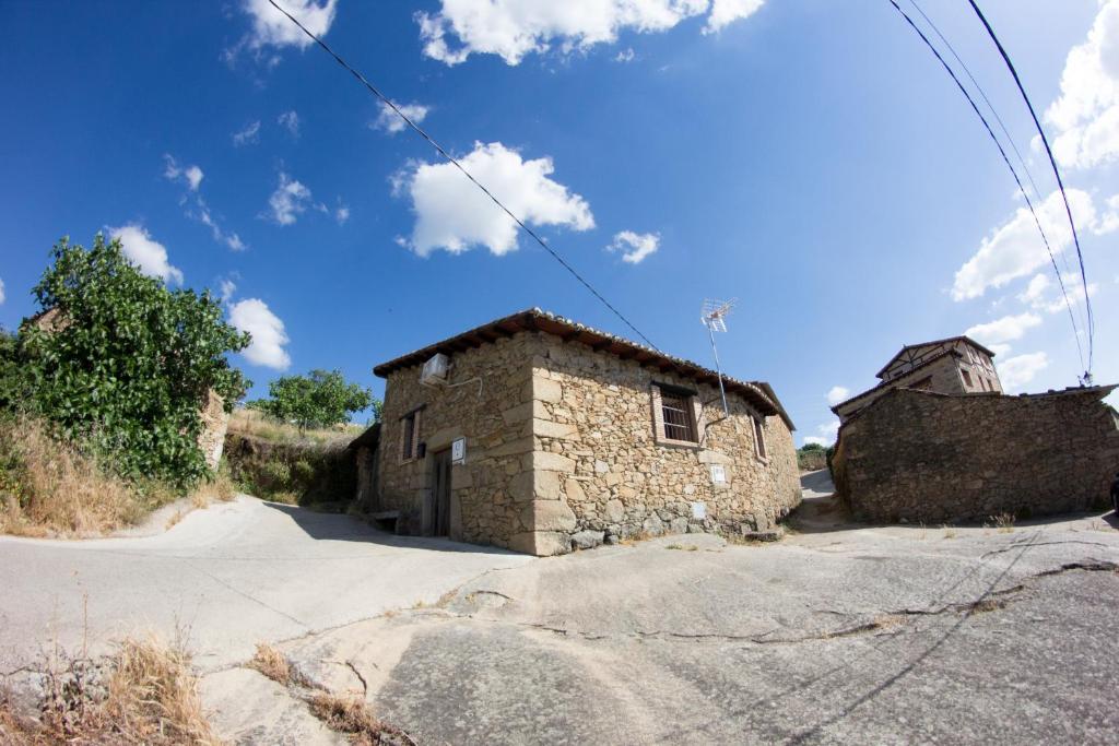 um edifício de pedra numa rua com um céu azul em CASA DE PIEDRA em Casas del Monte