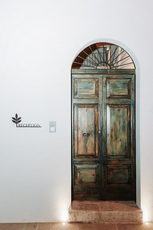 a wooden door in a white wall with a sign at CORTE LARGO LAURO DIMORE & SPA in Gemini