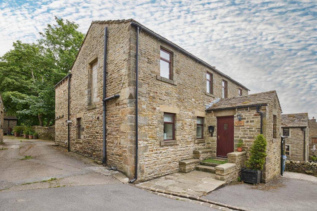an old brick house with a red door at Host & Stay - The Cottage Barn in Skipton