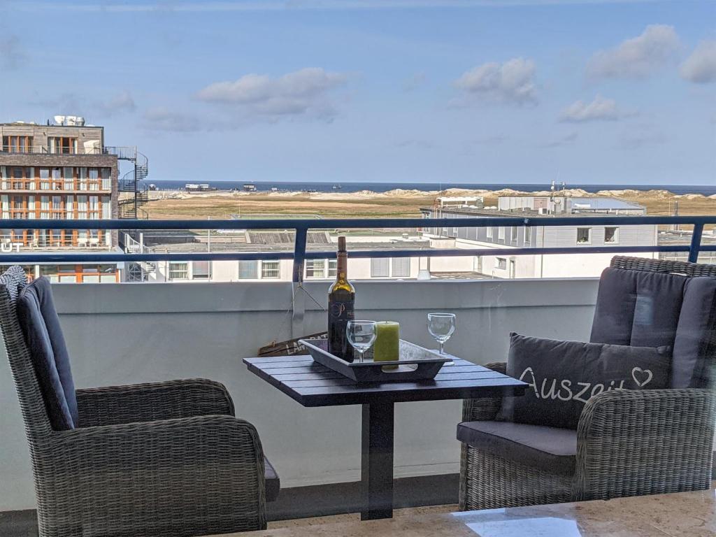 een tafel met een fles wijn en twee stoelen bij Luv & Lee - Meerblick 34 in Sankt Peter-Ording