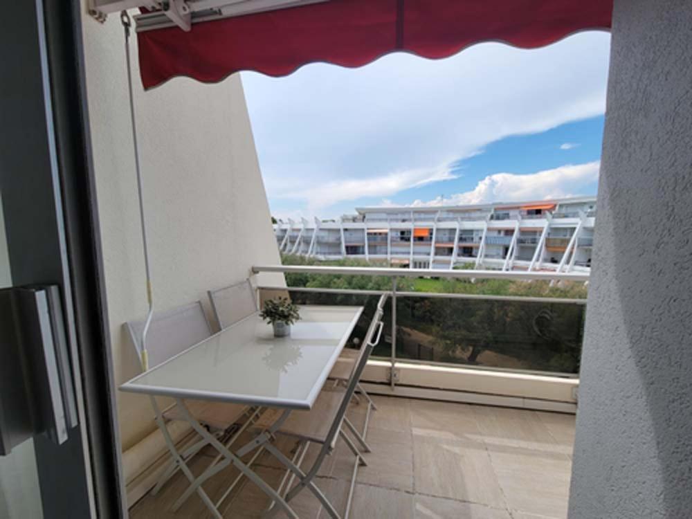 einen Tisch und Stühle auf einem Balkon mit Blick auf ein Gebäude in der Unterkunft Studio cabine climatisé avec parking au Couchant in La Grande-Motte