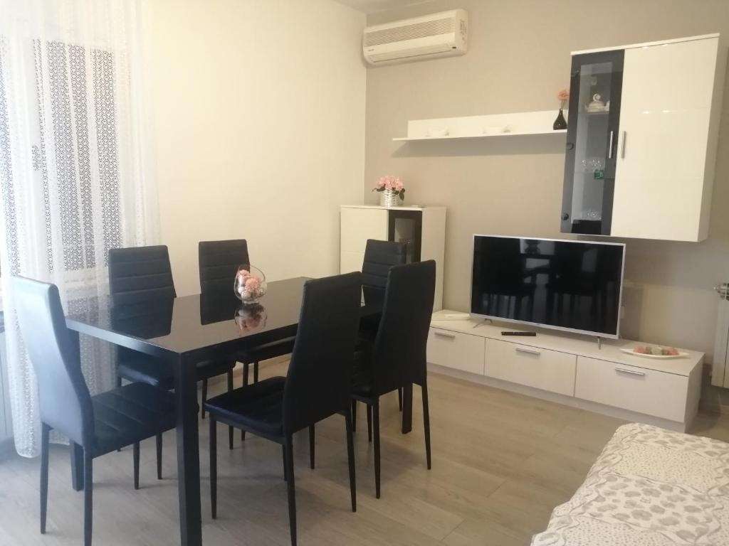 einen Esstisch mit schwarzen Stühlen und einem TV in der Unterkunft Apartment Vera, 80 m from the sea in Novigrad Istria