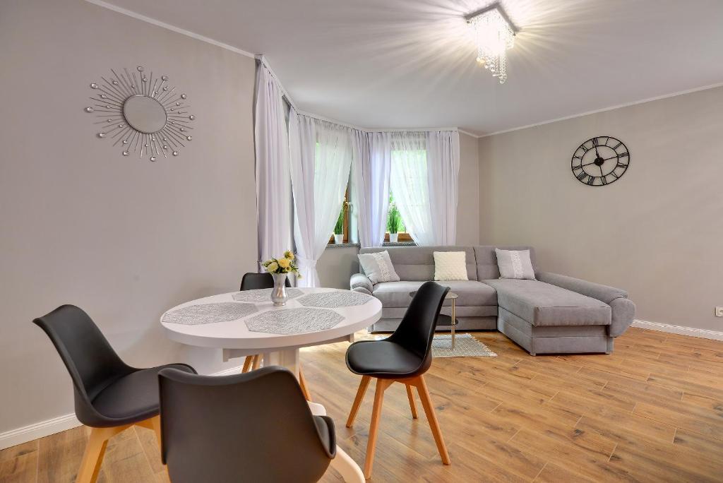 a living room with a couch and a table and chairs at Apartamenty Sun Seasons 24 - Nad Łomnicą Centrum in Karpacz