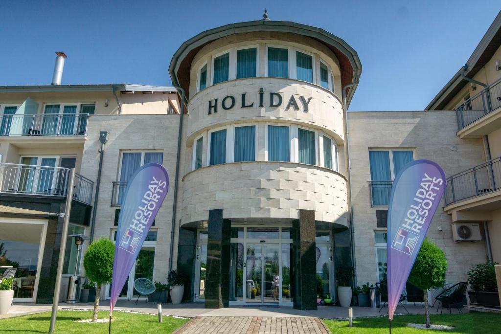 un edificio con signos púrpura delante de él en Holiday Resorts, en Balatonszárszó
