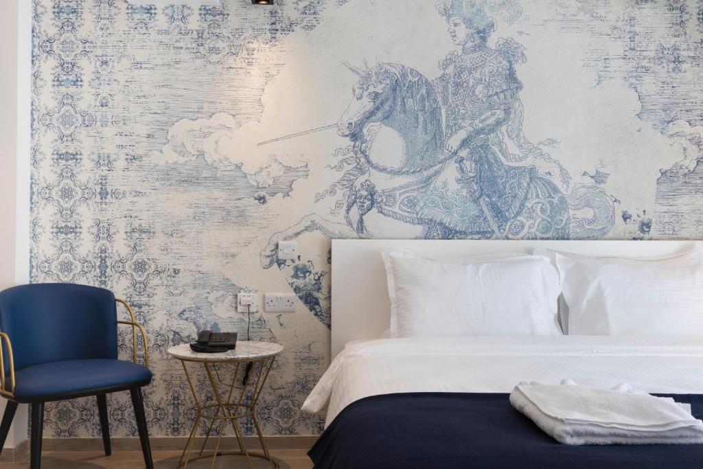 um quarto com uma cama branca e uma cadeira azul em The G Hotel by JL em St. Julian's