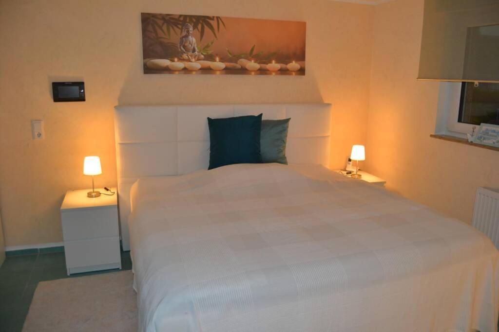 ein Schlafzimmer mit einem großen weißen Bett mit zwei Lampen in der Unterkunft Maison Madlene in Frickenhausen