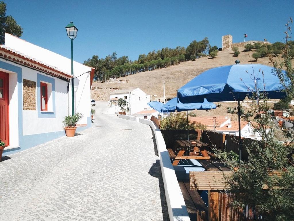 un patio con sombrillas y mesas y un edificio en Calma Aljezur, en Aljezur