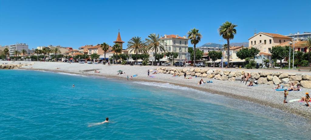 a beach with a bunch of people in the water at Studio de la plage - Mer, Terrasse et garage in Cagnes-sur-Mer