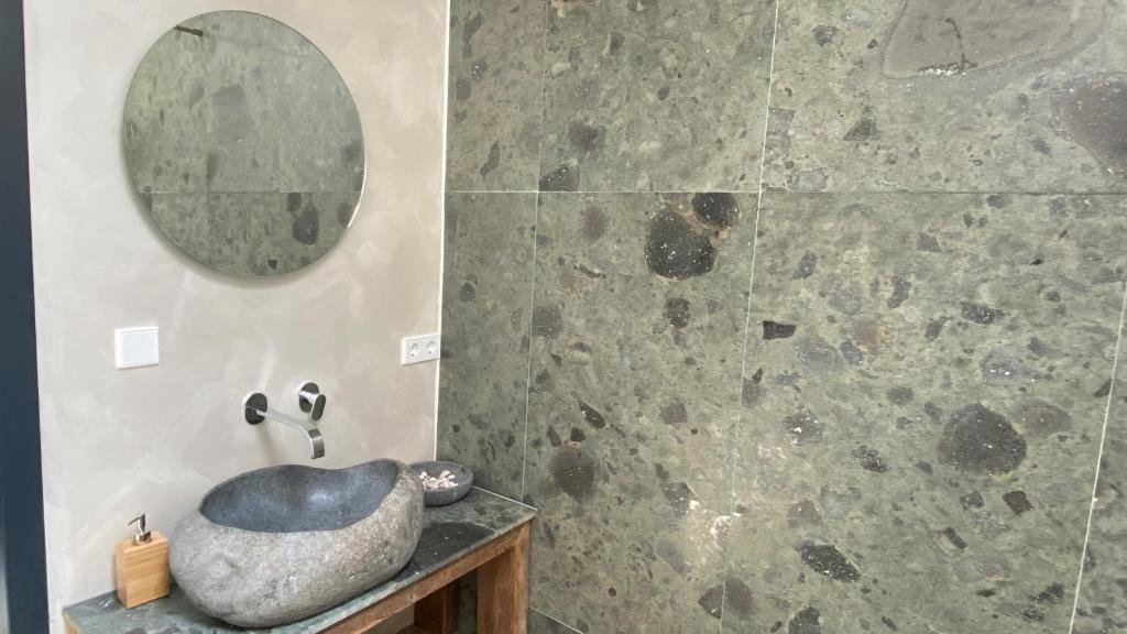 a bathroom with a stone sink and a mirror at Het Lichthuis in Zandvoort