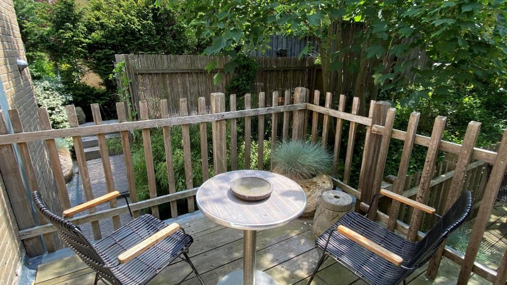a patio with a table and two chairs and a fence at Het Lichthuis in Zandvoort