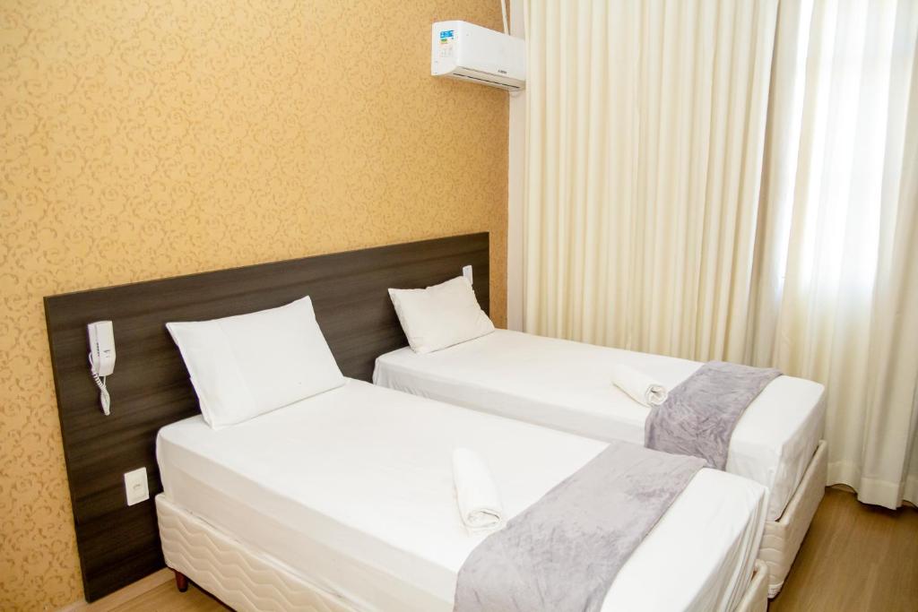 2 camas en una habitación de hotel con sábanas blancas en Hotel GMatos Belo Horizonte - By UP Hotel, en Belo Horizonte
