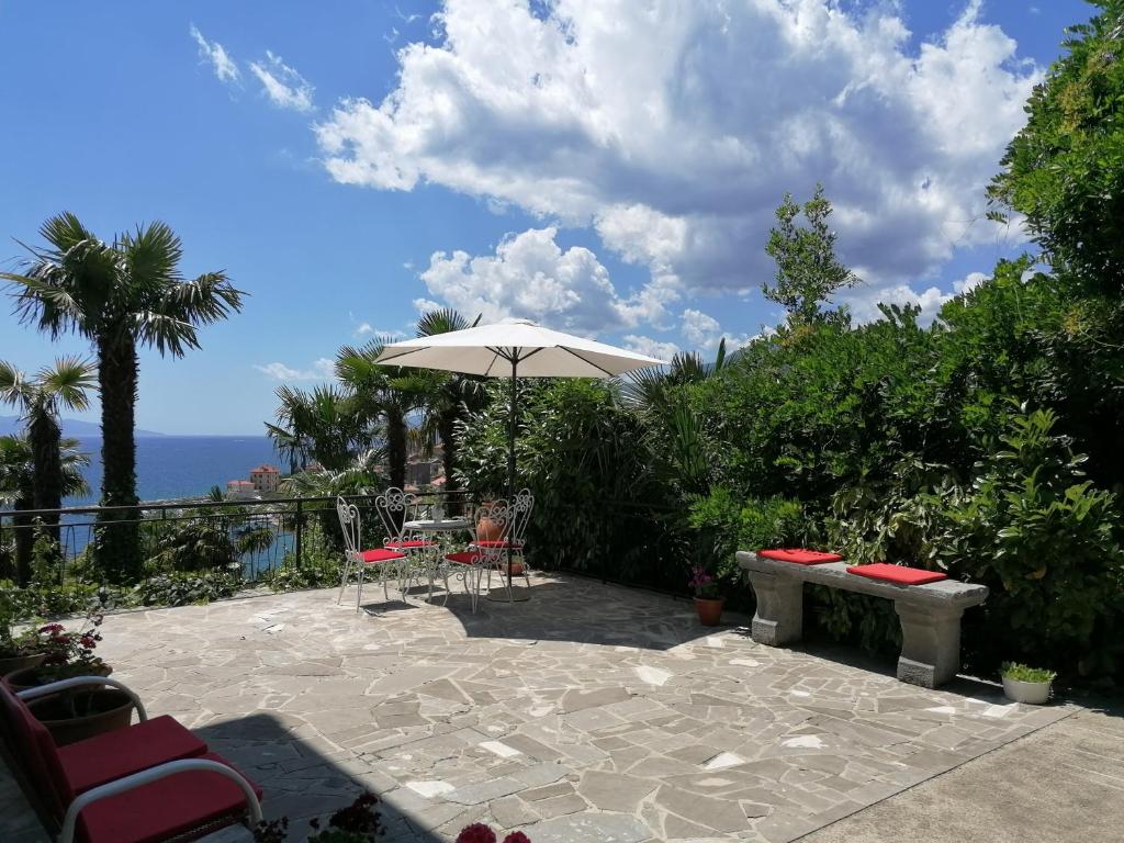 een patio met een parasol en een tafel en stoelen bij K&M Apartment in Opatija