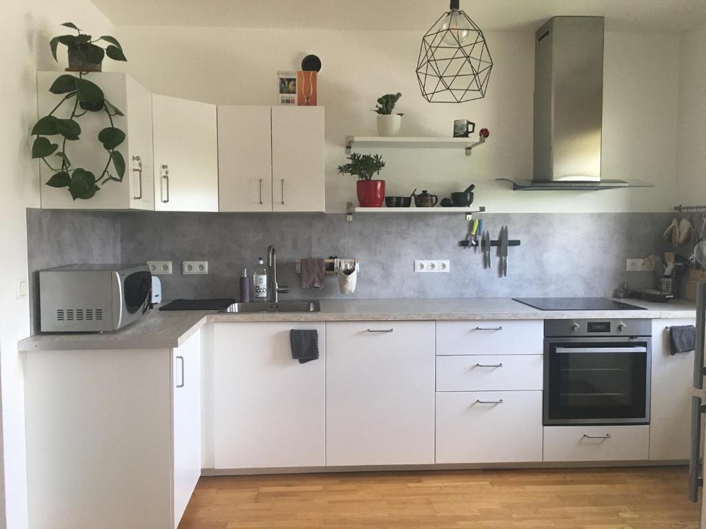 uma cozinha branca com armários brancos e um micro-ondas em Strelnieku Apartment em Sigulda